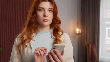 Carefree Caucasian woman girl touch screen using smartphone relaxed lady scrolling digital feed in social media Internet by mobile phone device at home calm female look in camera cyberspace connection photo