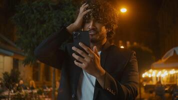 Indian Arabian Latino American man using mobile phone smartphone losing failure bad news messages annoyed dissatisfied unhappy guy hold head city outside evening mistake problem trouble breaking gen z photo