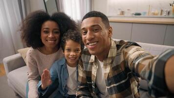 Smiling joyful young African American family mother father little boy son looking at camera making online call webcam hello talk waving hands greeting virtual chat meeting indoors apartment home photo