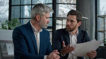 Two disgruntled furious Caucasian businessmen arguing about bad contract in office men colleagues partners dispute incorrect document failed transaction deal conflict problem shouting break agreement photo