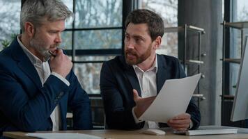 Two disgruntled furious Caucasian businessmen arguing about bad contract in office men colleagues partners dispute incorrect document failed transaction deal conflict problem shouting break agreement photo