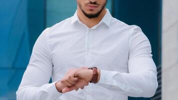 Unrecognizable business man boss leader manager wears white formal shirt looks at wrist watch angry of late time lateness checks hour negative upset lateness meeting with partner photo
