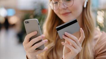 Close-up young girl hands holding smartphone and credit card happy woman customer make online purchase pay bills using banking app on phone virtual remote shopping successful safe transaction concept photo