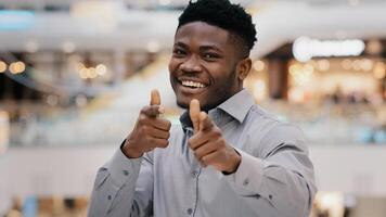 Close-up happy young handsome african american man looking at camera smiling posing showing gesture hey you pistols making choice approval sign consent symbol pointing fingers demonstrates support photo