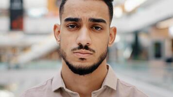 Close-up of face upset young man sad frustrated millennial guy looking at camera serious hispanic male having negative thoughts depressive mood difficult period life misunderstanding problems at work photo