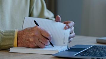 Unrecognizable mature man sit at workplace professor preparing lecture for students remote presentation author create handwritten text pensioner with wrinkles hands make notes writes memories in diary photo