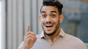 Close-up male pensive face, portrait hispanic puzzled business man professional standing outdoors deep in thoughts thinking recollecting memory creating plan raises index finger comes up with idea photo