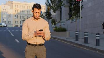 Stylish bearded hispanic businessman stand in city center street uses mobile phone texting scrolling tapping app technology online communication with smartphone success chatting with gadget device photo