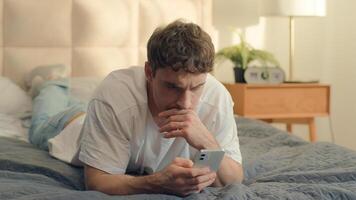 Serious Caucasian man bed using mobile phone smartphone guy male technology pensive problem frown error rejection fail broken gadget spam connection notification stressful worry wrong trouble banking photo