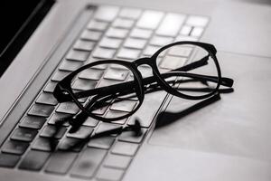 Sleek eyewear placed on a laptop keyboard, highlighting the importance of tech solutions for digital eye care. Perfect for frequent computer users photo