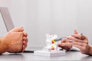 Close-up of a doctor hands demonstrating a detailed medical explanation using a spine model. Ideal for showcasing expert knowledge, patient education, and healthcare professionalism photo