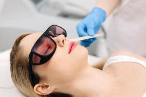 Aesthetician prepares a client skin for laser hair removal by applying cooling gel in a modern spa. Highlighting advanced skincare procedures in a professional and serene environment photo