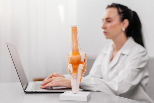Orthopedic surgeon shows a detailed knee joint model during a medical consultation, demonstrating treatment methods. Ideal for illustrating expert medical advice and advanced orthopedic care photo