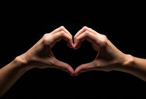 Hands gesture forming heart shape on black background photo