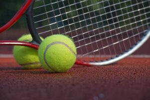 Close-up of tennis ball and racket against net on clay court photo