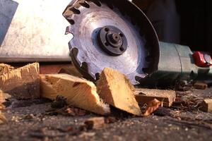 Circular saw blade cutting through logs with wood shavings and debris in a rustic workshop setting photo