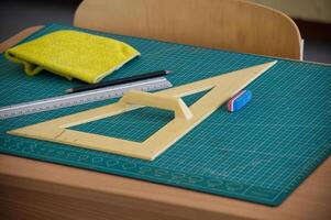 Classroom desk with math tools, ruler, and eraser on a cutting mat photo