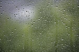 Window surface covered with many water droplets of various sizes, creating a textured pattern photo