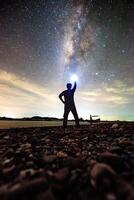 Silhouette of Person Holding Light Under Starry Night Sky with Milky Way in Background photo
