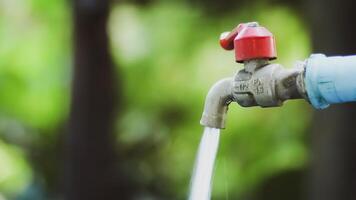 Close-Up of Outdoor Water Faucet with Flowing Water Against Blurred Green Background photo