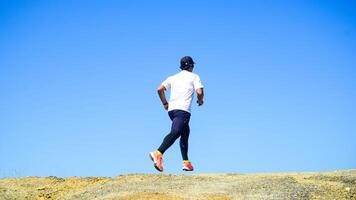Man Running Outdoors on a Sunny Day with Clear Blue Sky in the Background photo