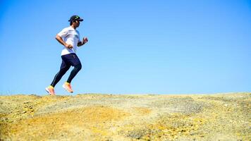 Athletic Man Running Outdoors on a Sunny Day with Clear Blue Sky in the Background photo