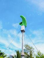 Green Wind Turbine Against a Clear Blue Sky with Trees in the Background on a Sunny Day photo
