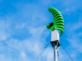 Modern Green Wind Turbine Against Blue Sky with Clouds on a Clear Day photo