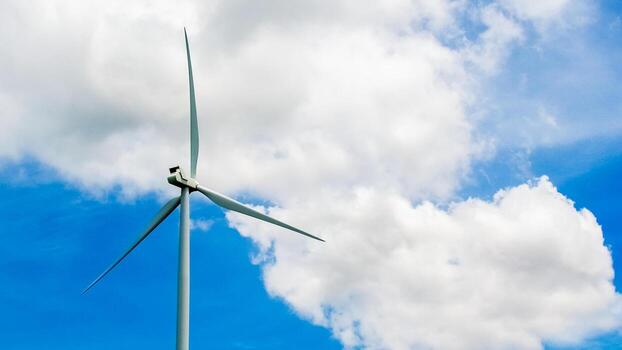 Wind Turbine Against Blue Sky with White Clouds - Renewable Energy Source and Sustainable Power Generation photo