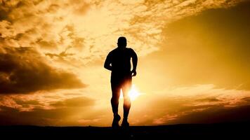 Silhouette of a Man Running at Sunset with Dramatic Sky and Golden Light in the Background photo