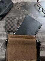 Leather bag with gadgets and notebooks on Wooden Work Desk photo