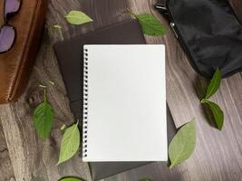 Still life photography blank notebook on wooden table with a cup of coffee, plant, leaf on table photo