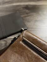 Leather bag with gadgets and notebooks on Wooden Work Desk photo