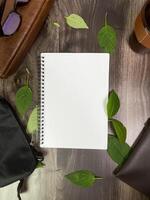 Still life photography blank notebook on wooden table with a cup of coffee, plant, leaf on table photo