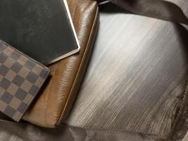 Leather bag with gadgets and notebooks on Wooden Work Desk photo