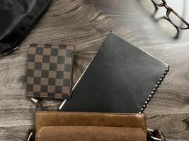 Leather bag with gadgets and notebooks on Wooden Work Desk photo