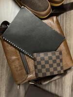 Leather bag with gadgets and notebooks on Wooden Work Desk photo