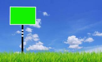 Blank Green Billboard in a Grassy Field with Blue Sky and White Clouds in the Background photo
