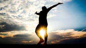 Silhouette of a Person Celebrating Freedom Against a Dramatic Sunset Sky with Clouds photo