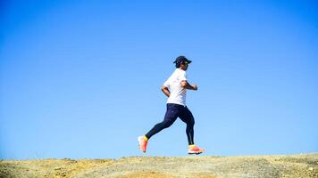Man Running Outdoors on a Sunny Day with Clear Blue Sky in the Background photo