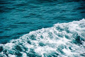 Aerial View of Turquoise Ocean Waves Crashing and Creating White Foam on a Sunny Day photo