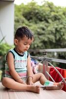 Cute Indian boy holding Indian National Flag in his hangs at home balcony. Bright portrait of happy child sitting on the table with national flag photo
