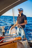 Young man captain stands at the helm and controls a sailboat during a journey by sea. High quality photo