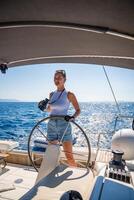 Young female captain on the yacht looking through binoculars during sailing boat control. Travel and active life. Yachting. High quality photo