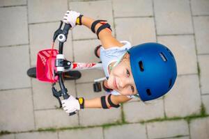 Top view of little girl rides a two-wheeled bicycle Ii the courtyard of apartment buildings in summer, Europe. High quality photo