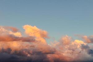 Dramatic clouds in the blue sky in the morning, the rising sun rays hitting the clouds photo