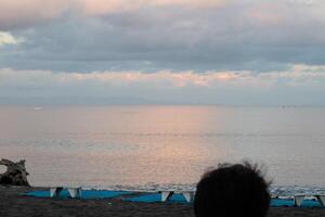 Dramatic clouds in the blue sky above the ocean, the rising sun rays hit the clouds photo
