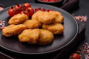 Delicious fresh crispy chicken nuggets on a dark concrete background photo