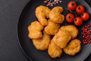Delicious fresh crispy chicken nuggets on a dark concrete background photo