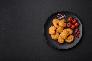 Delicious fresh crispy chicken nuggets on a dark concrete background photo